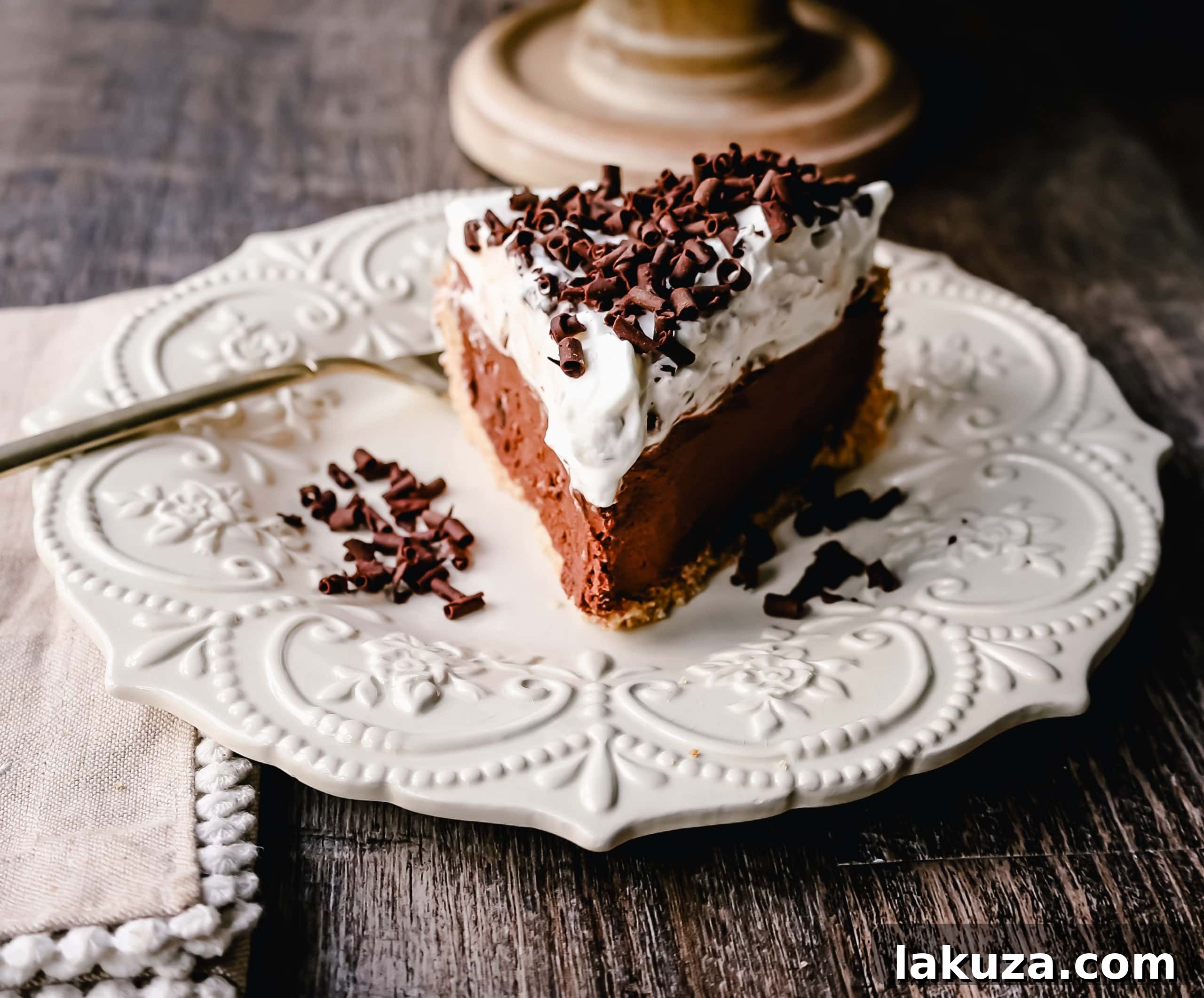 French Silk Pie garnished with generous swirls of homemade whipped cream and elegant chocolate shavings, ready for serving.