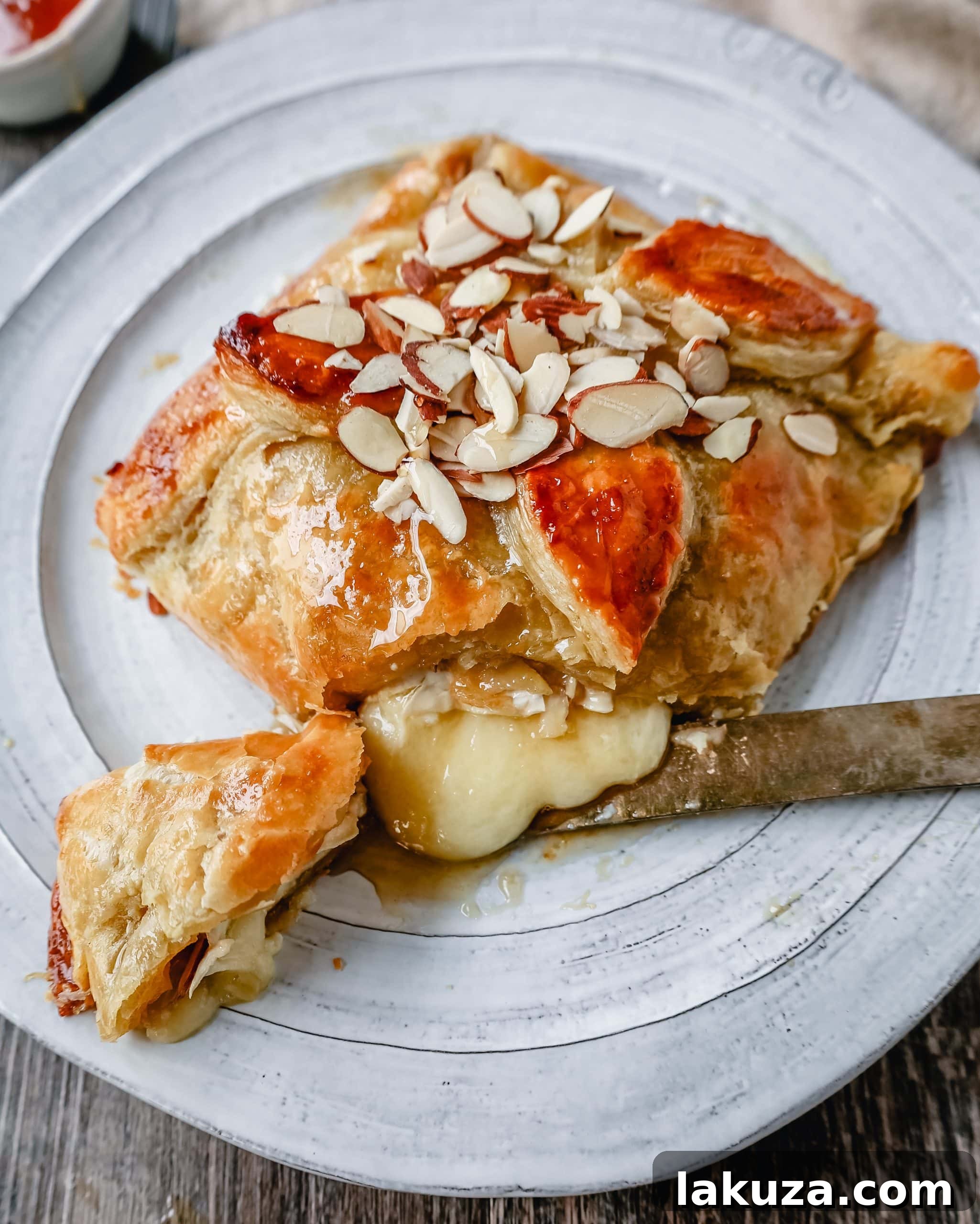 Close-up of the Honey Almond Puff Pastry Wrapped Brie, showcasing its golden crust and almond topping.