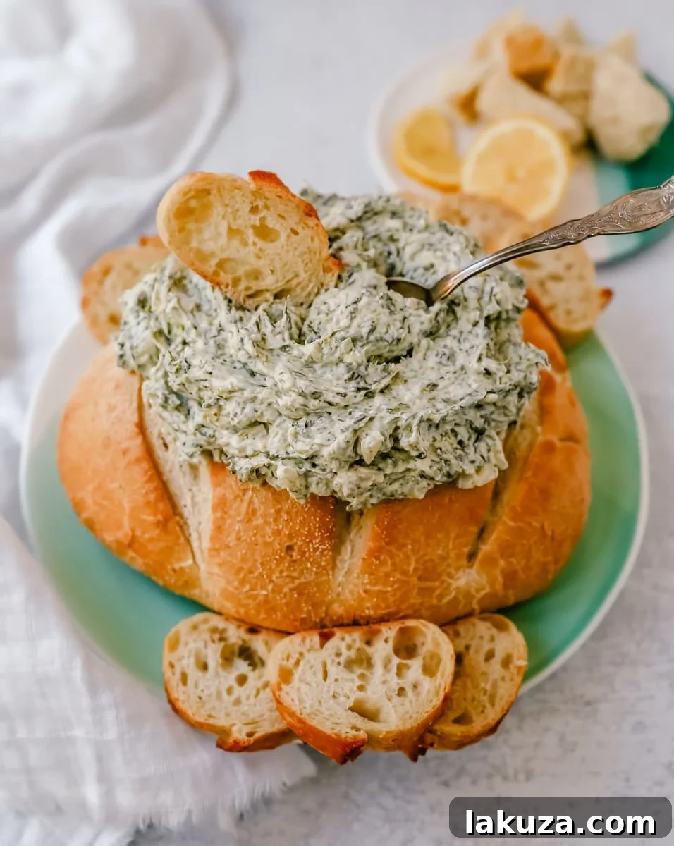 Close-up of a bowl of creamy cold spinach dip, showing the flecks of spinach and chopped water chestnuts, ready for serving.