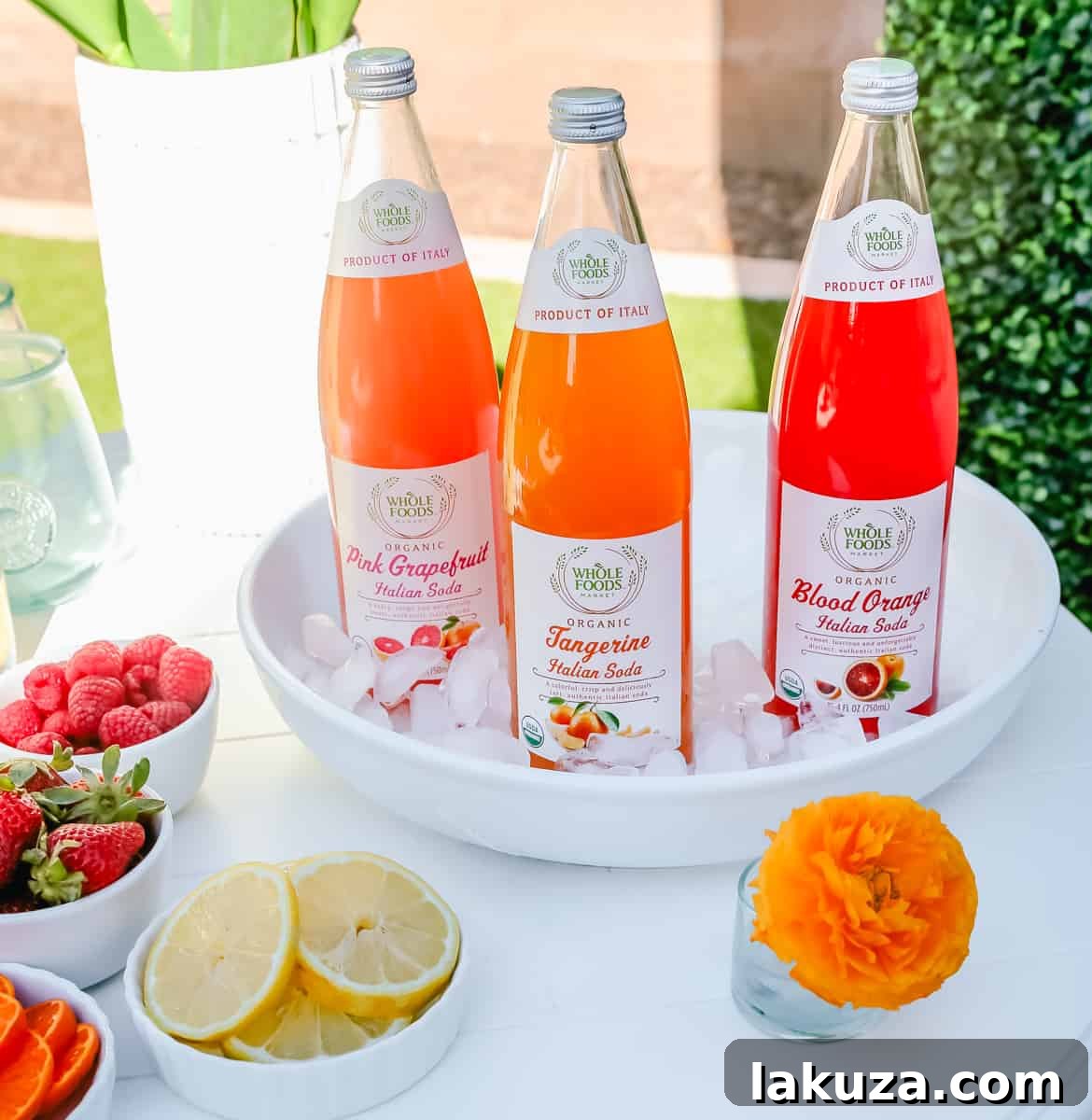 An inviting Italian Soda Drink Bar, complete with various soda flavors, fresh fruit garnishes, and elegant serving glasses. An excellent non-alcoholic drink station idea for a spring or Easter brunch party.
