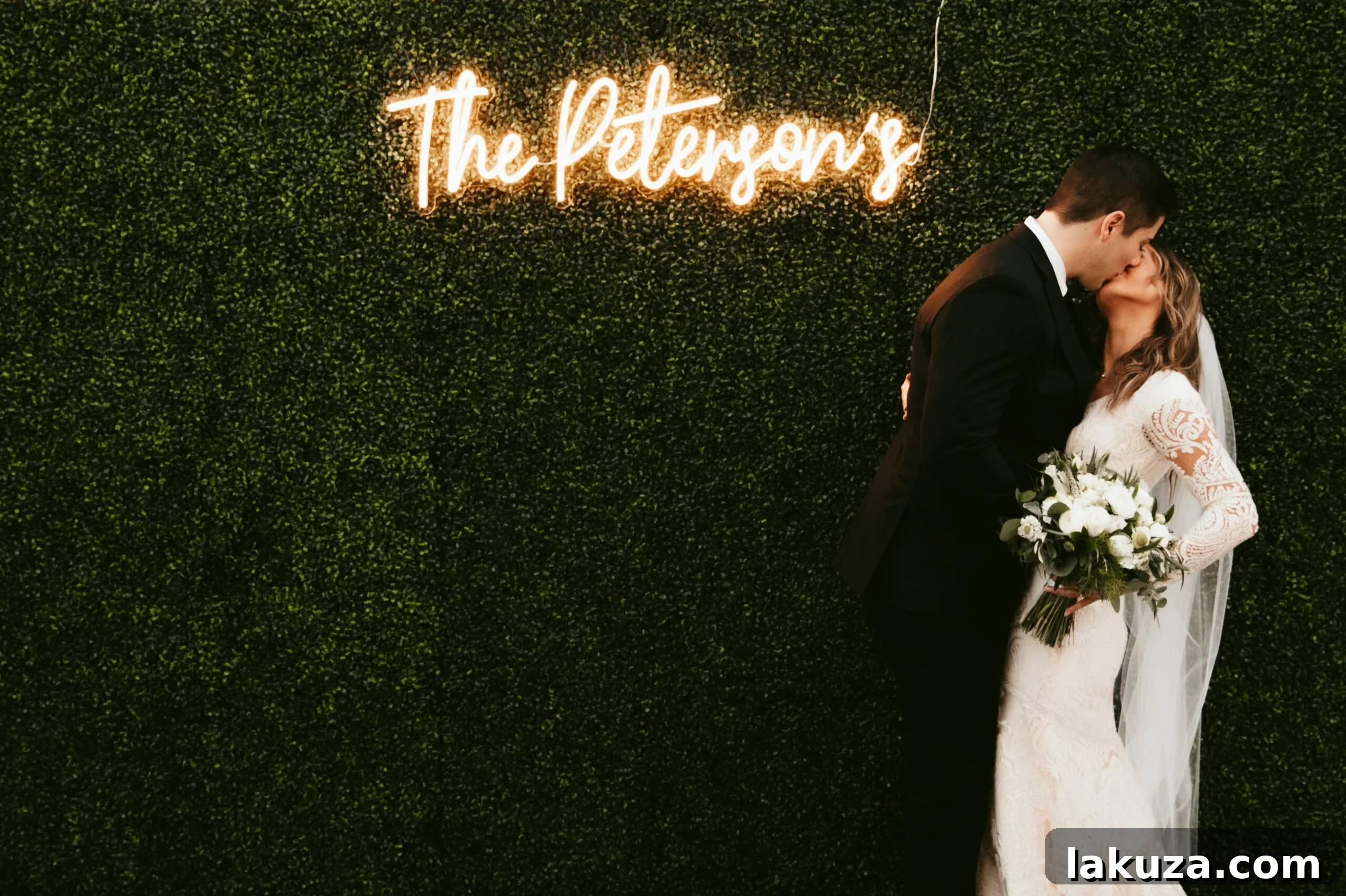 Close-up of wedding guests posing in front of the greenery wall
