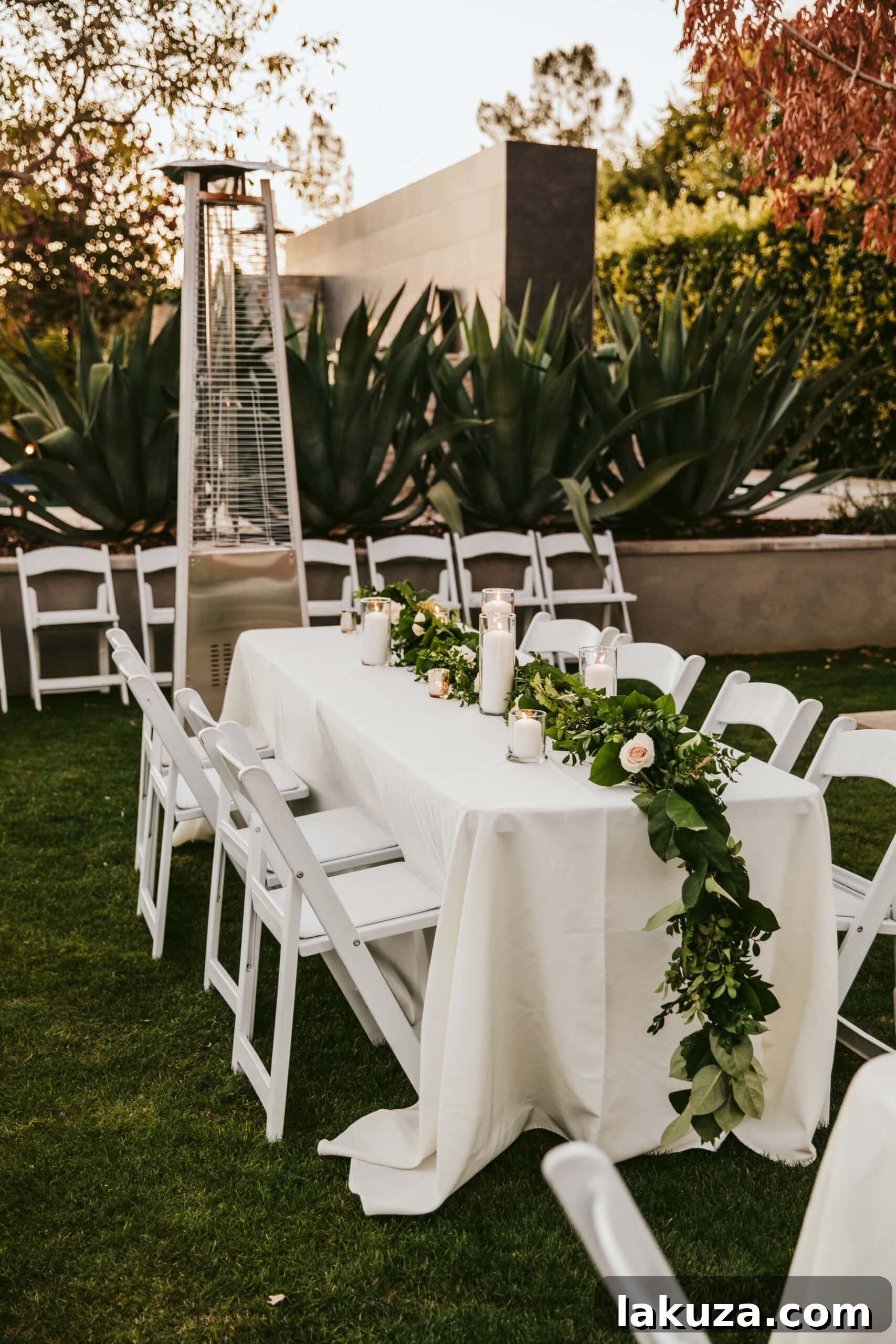 Wedding table centerpiece with greenery garland, white roses, and candles