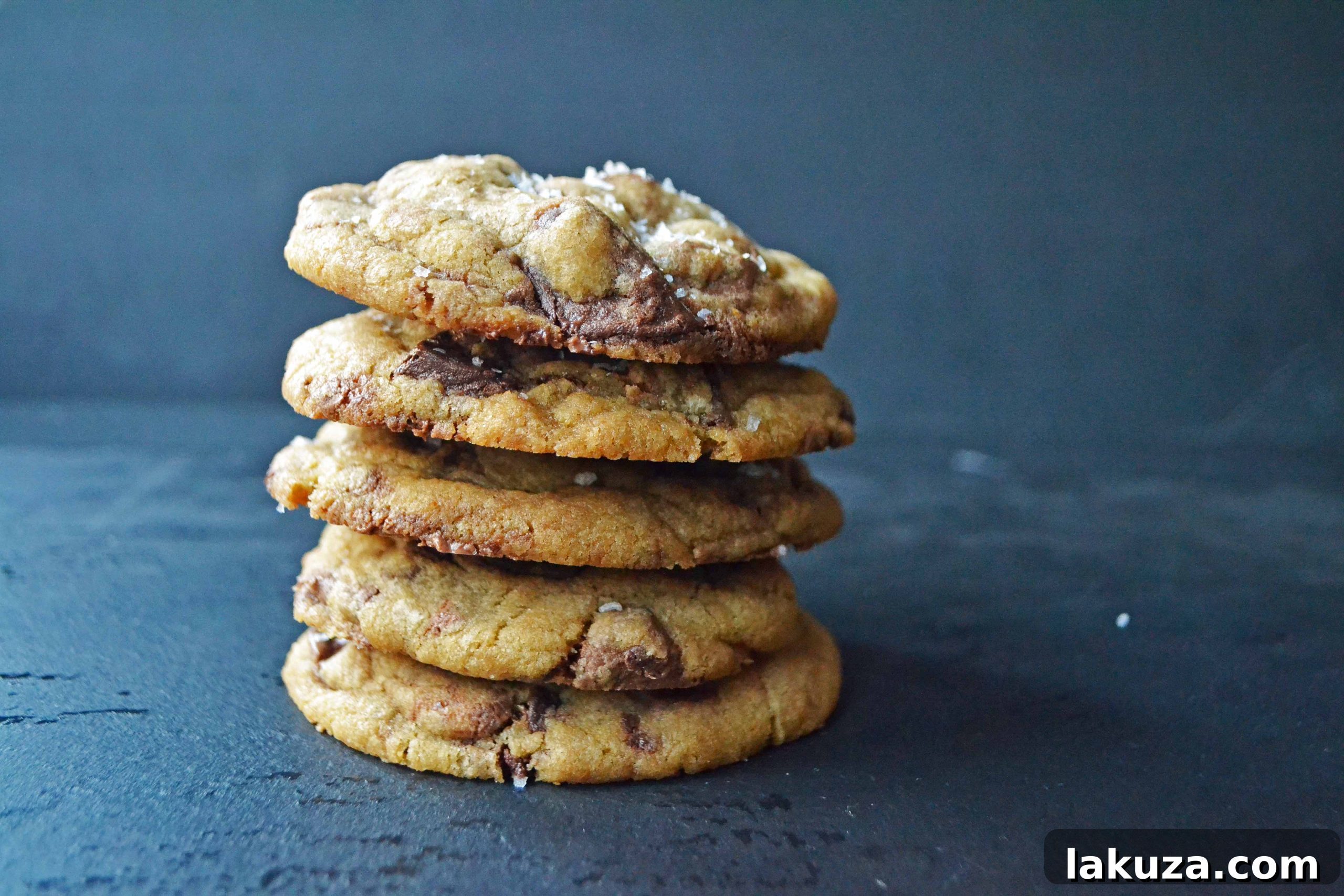 A stack of warm browned butter chocolate chip cookies, each boasting a perfect golden color and inviting texture.