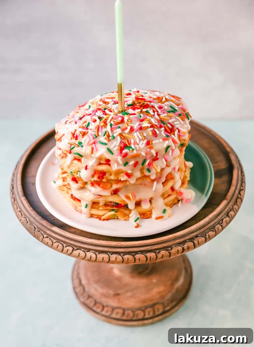 Ingredients for homemade birthday sprinkle pancakes, including flour, buttermilk, eggs, and a bowl of bright rainbow sprinkles, arranged on a rustic wooden surface.