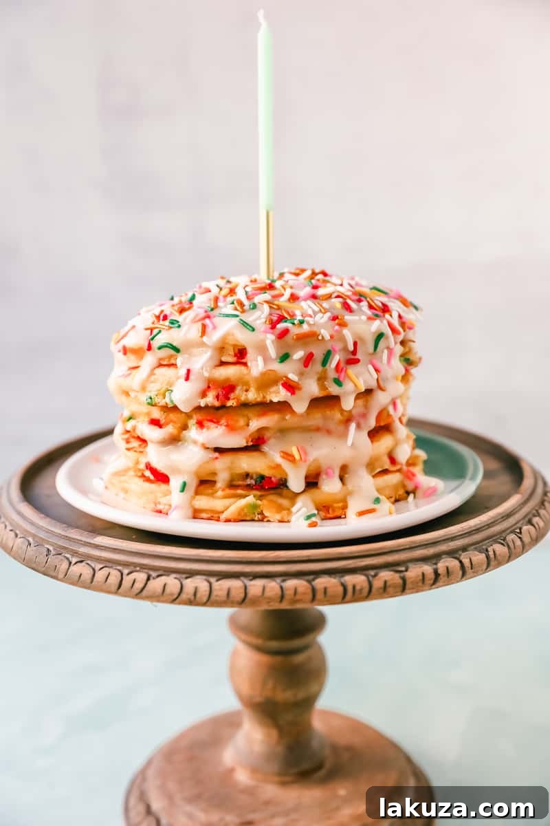 A plate of freshly cooked buttermilk pancakes with rainbow sprinkles, partially drizzled with cream cheese glaze, and garnished with extra sprinkles, perfect for a festive breakfast.