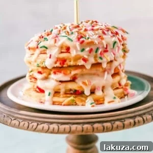 A visually appealing stack of birthday sprinkle pancakes with cream cheese glaze, showcasing the vibrant colors and fluffy texture of this celebratory breakfast.