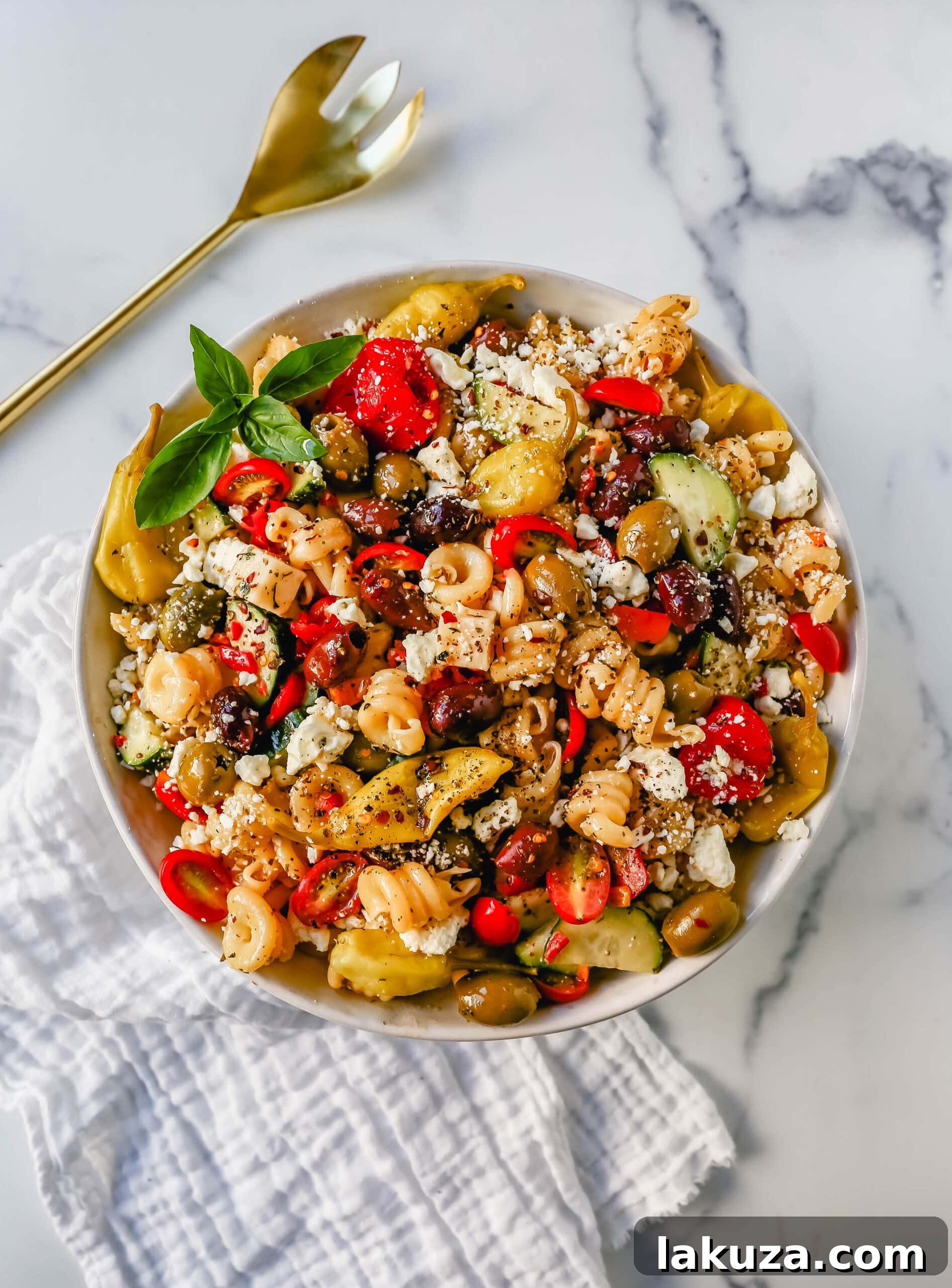 A bowl of vibrant Greek Pasta Salad, ready to be served, highlighting its fresh ingredients.
