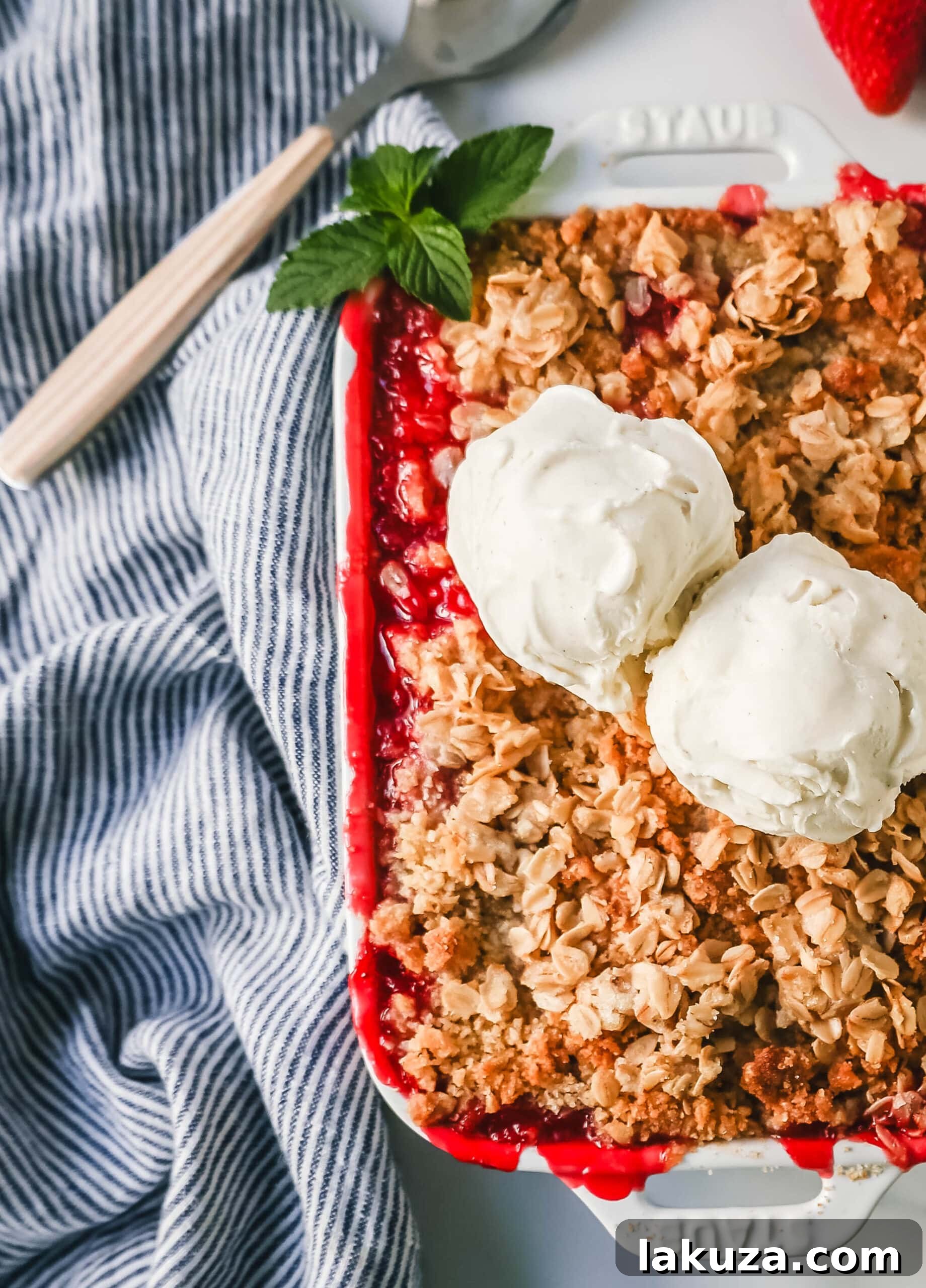A close-up view of the perfectly baked Strawberry Crisp, showcasing the golden-brown oat topping and the rich, red strawberry filling bubbling beneath. Ready to be served.