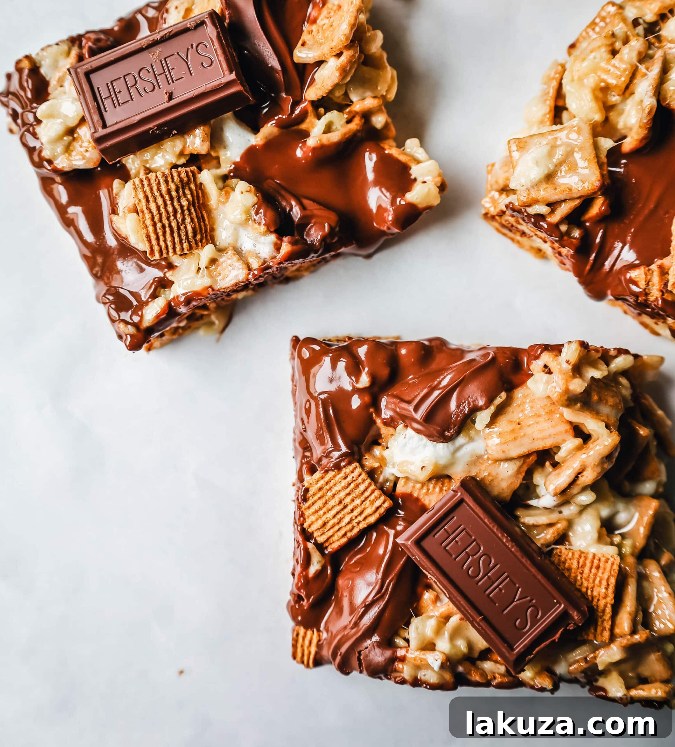 A close-up of S'more Rice Krispie Treats, showing the layers of Golden Grahams, Rice Krispies, marshmallows, and melted Hershey's chocolate, ready to be cut.