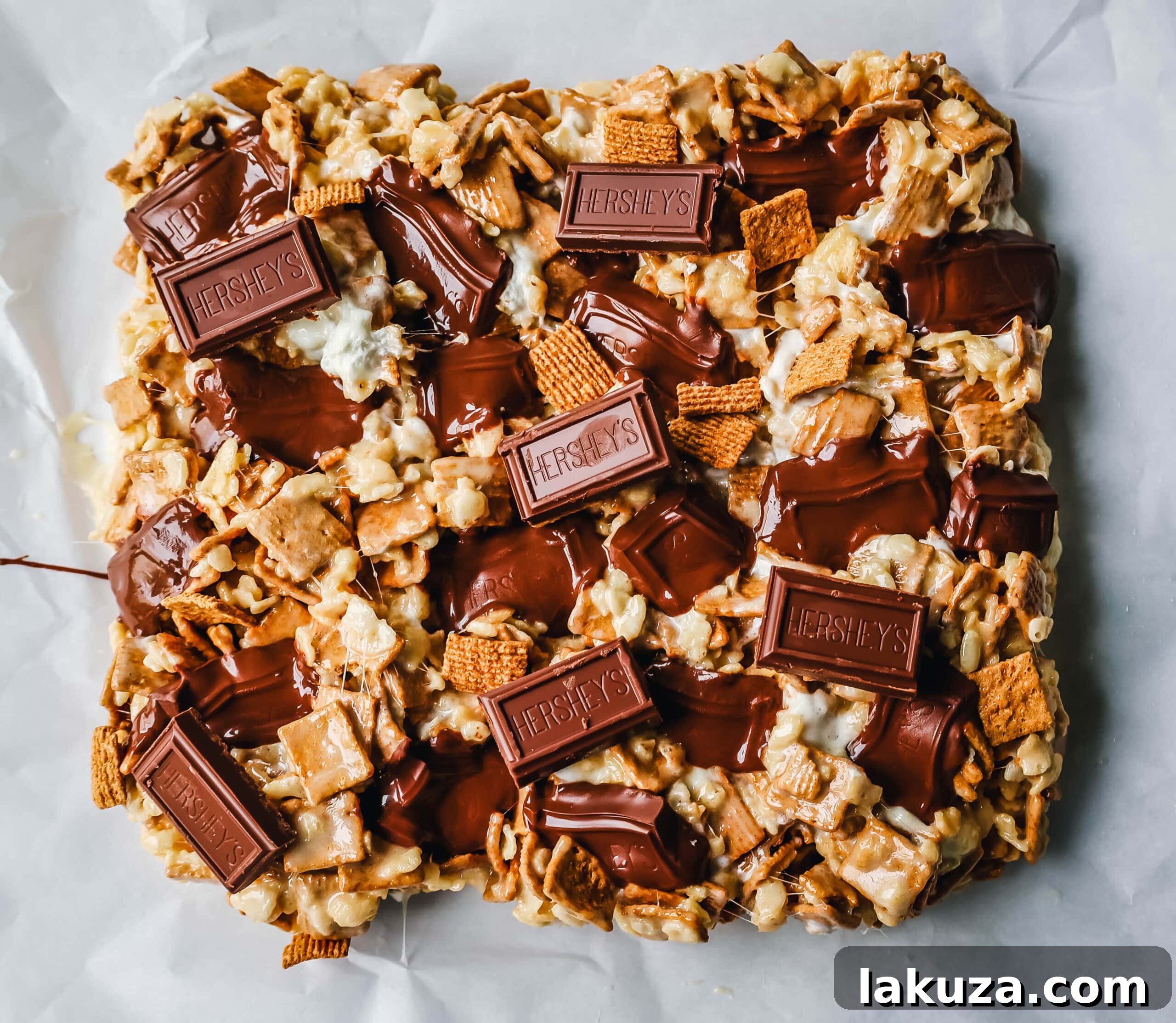 A tray of freshly made S'more Rice Krispie Treats with Golden Grahams and chocolate pieces on top, ready for cooling.