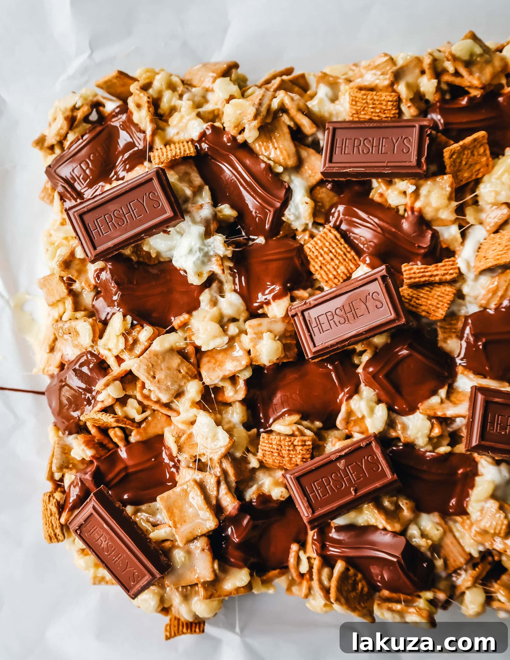 Multiple S'more Rice Krispie Treats, cut into squares, with visible layers of cereal, marshmallow, and chocolate, arranged on a plate.
