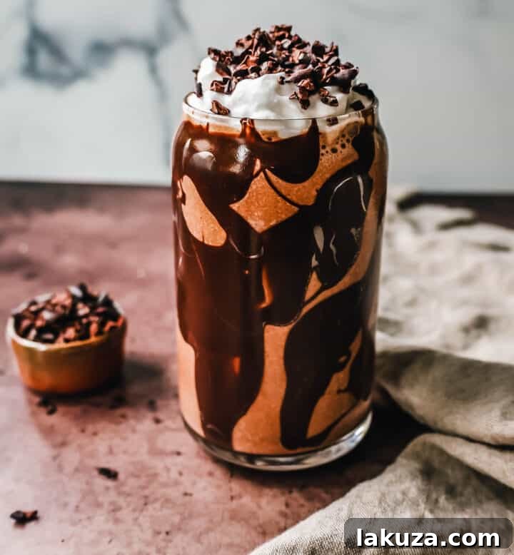 A perfectly blended Chocolate Almond Butter Smoothie garnished with whipped cream and cacao nibs.