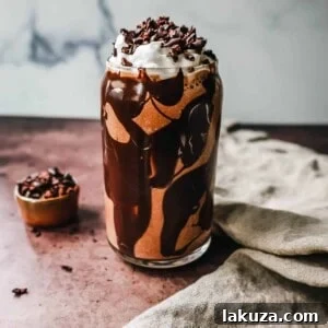 A glass of Chocolate Almond Butter Smoothie topped with whipped cream and cacao nibs.