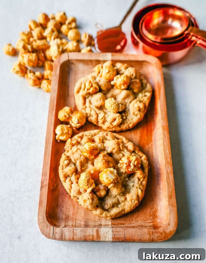 Sweet & Salty Popcorn Caramel Delights 3 A close-up of a freshly baked Caramel Popcorn Cookie, showcasing its rich brown sugar dough and embedded caramel popcorn pieces, sprinkled with sea salt flakes.