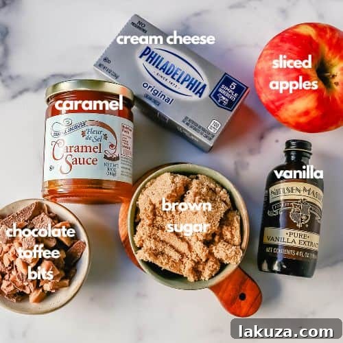 A beautifully presented Caramel Toffee Dip in a small white square dish, generously topped with glistening caramel sauce and abundant toffee bits. A neatly arranged pile of red apple slices sits beside the dip, ready for serving.
