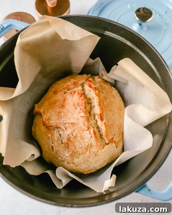 Effortless Overnight Artisan Loaf 16 A beautifully sliced No-Knead Dutch Oven Bread, revealing its airy texture and golden crust, served with fresh butter on a wooden board.