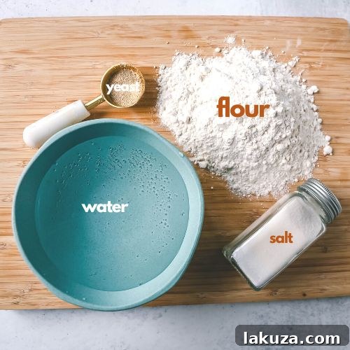 Effortless Overnight Artisan Loaf 4 A collection of the four essential ingredients for no-knead bread: a bowl of all-purpose flour, a jar of active dry yeast, a small dish of salt, and a glass of warm water, neatly arranged on a wooden surface.