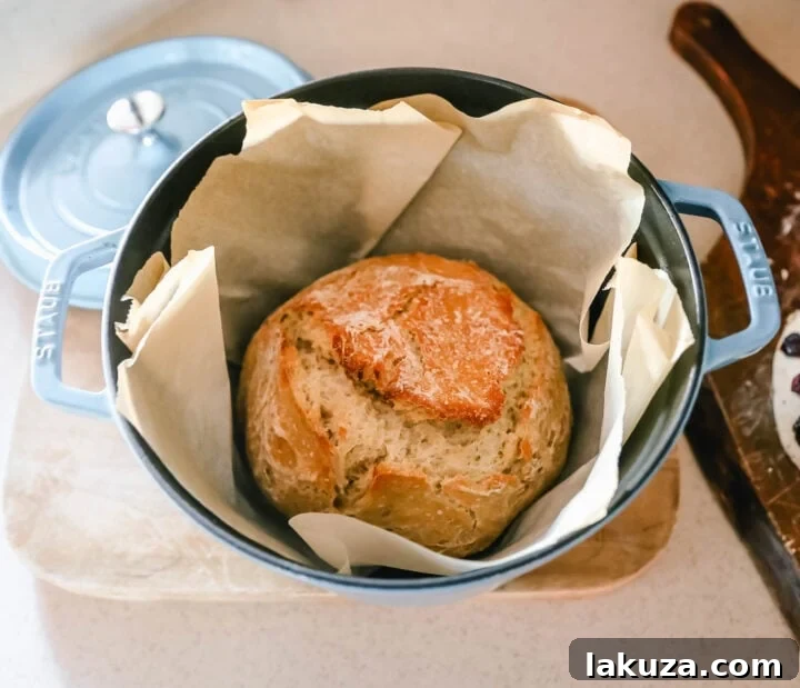 Effortless Overnight Artisan Loaf 7 A rustic scene of a golden-brown no-knead bread loaf cooling on a wire rack in a cozy cabin setting, emphasizing the homemade artisan quality.