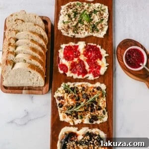 A festive Butter Board with a variety of sweet and savory toppings, served with warm bread, perfect for a party appetizer.