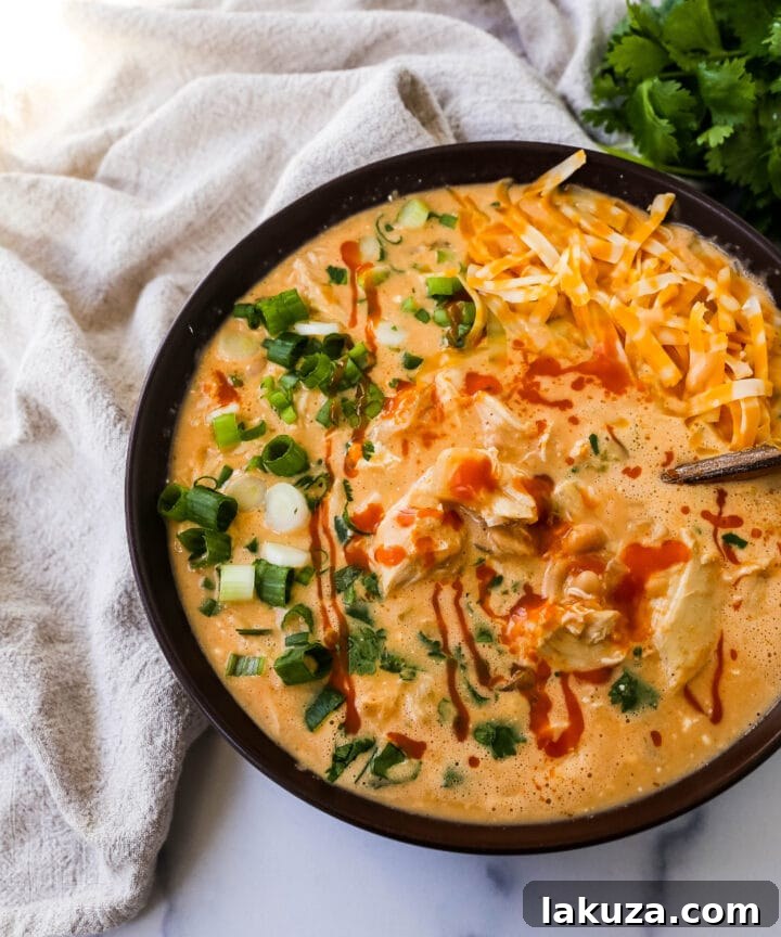 Bold Buffalo Chicken Chili 2 A steaming bowl of creamy buffalo chicken chili, garnished with green onions and cilantro, showcasing its rich texture and vibrant color. This chili offers a perfect balance of spice, creaminess, and tang.