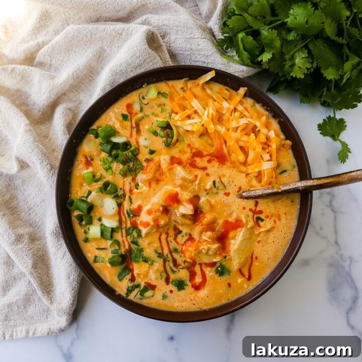 Bold Buffalo Chicken Chili 4 Overhead shot of creamy buffalo chicken chili in a bowl, topped with a generous sprinkle of chopped green onions and fresh cilantro, ready to be enjoyed.