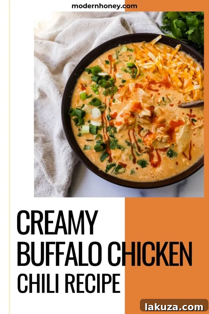 Bold Buffalo Chicken Chili 6 A vibrant and appetizing serving of creamy buffalo chicken chili in a bowl, with a spoon nestled in, inviting you to taste. Topped with fresh herbs and cheese.
