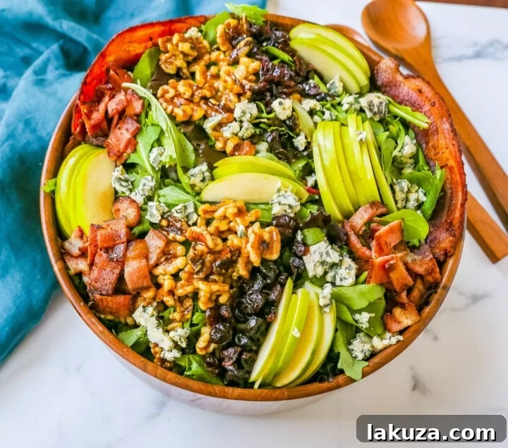 A beautifully presented Fall Harvest Salad, showcasing fresh apple slices, candied walnuts, dried cranberries, crumbled cheese, and crispy bacon, on a bed of greens, with a side of homemade apple cider vinegar dressing.