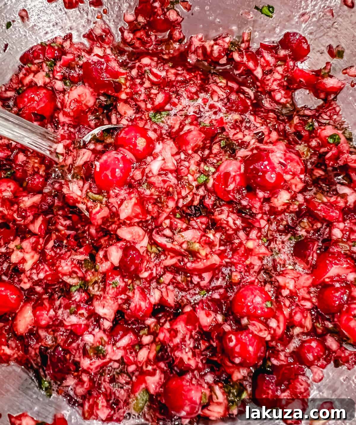 An overhead shot of the Cranberry Jalapeno Cream Cheese Dip garnished with fresh cranberries and herbs, presented on a rustic wooden board.