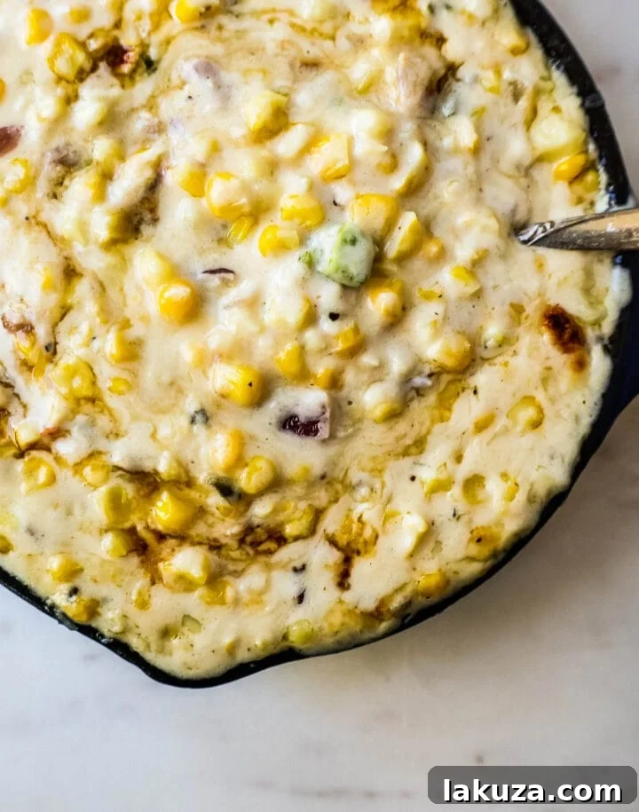 A large skillet filled with creamy Southwest corn, showing its rich texture and colorful ingredients.