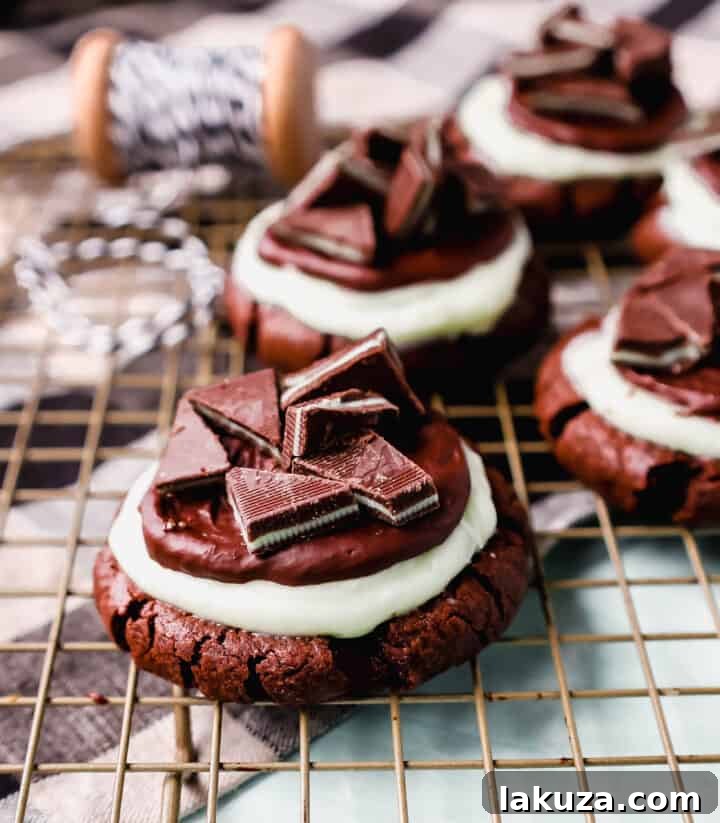 A tantalizing close-up of Frosted Mint Chocolate Brownie Cookies, showcasing the layers of rich cookie, mint frosting, and chocolate ganache, topped with Andes mints – a perfect holiday treat.