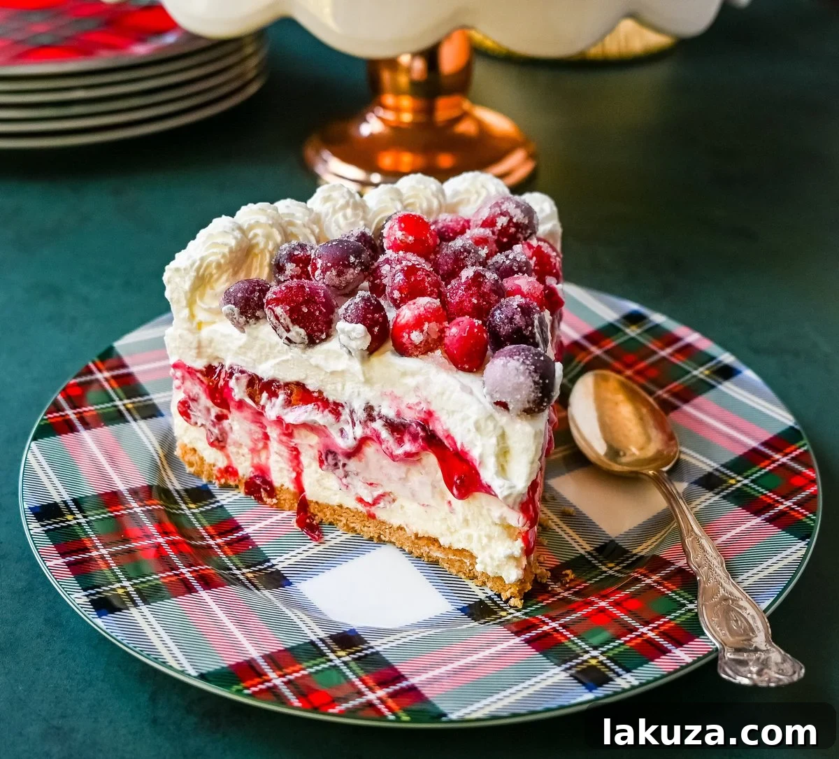 No-Bake Cranberry White Chocolate Cheesecake, a stunning festive dessert with a graham cracker crust, white chocolate cream cheese filling, homemade cranberry jam, sugared cranberries, and whipped cream.