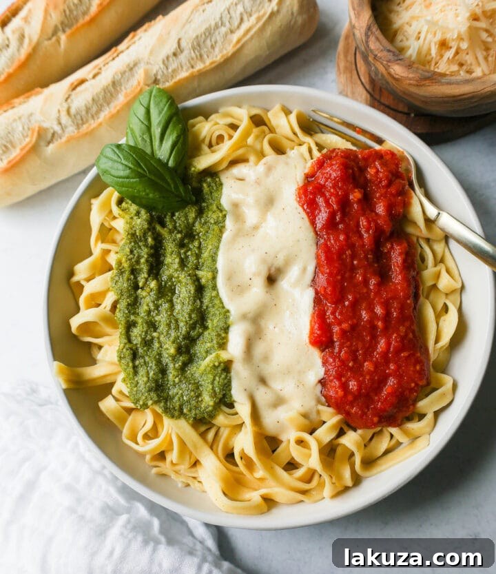 Beautifully arranged Christmas Pasta with distinct stripes of Alfredo, Marinara, and Pesto sauces before tossing.