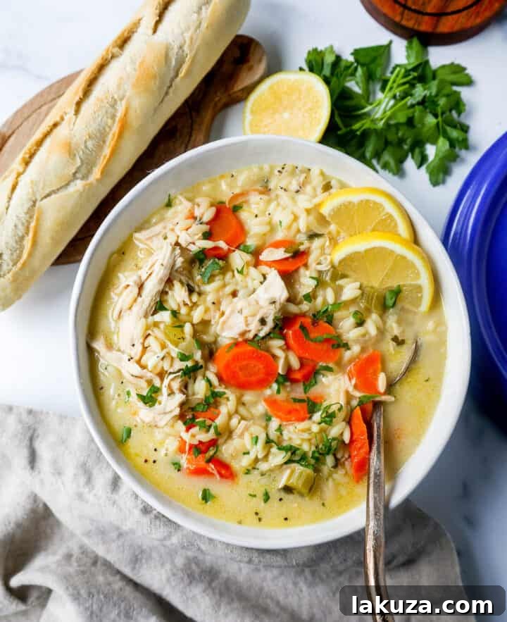 A close-up of a bubbling pot of Lemon Chicken Orzo Soup on the stovetop, showcasing its creamy texture and rich ingredients.