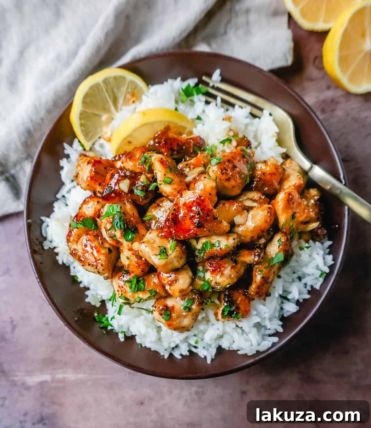 Close-up of golden-brown Honey Chicken pieces in a sticky lemon garlic sauce, cooked in a skillet.