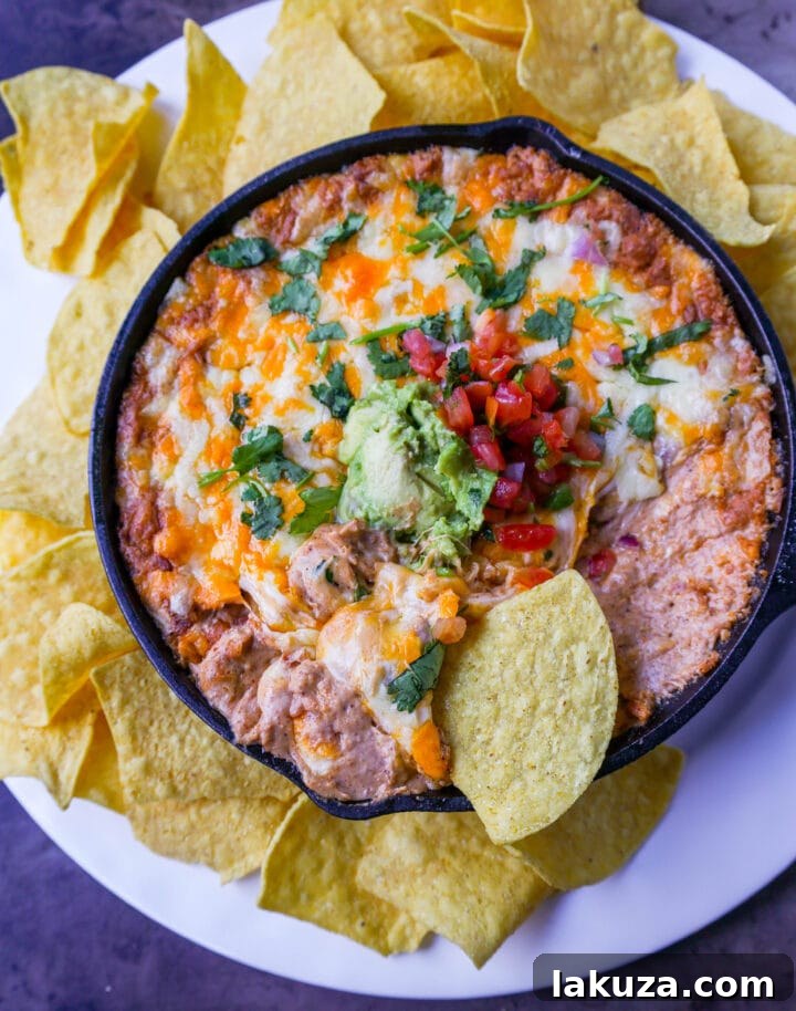 Close-up shot of a creamy, hot bean and cheese dip, ready to be served with tortilla chips. Highlights the melted cheese and a sprinkle of fresh cilantro.