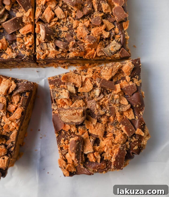 Ultimate Butterfinger Crunch Bars 4 Ingredients for making homemade Butterfinger bars laid out: graham crackers, sweetened condensed milk, butter, Butterfinger candy, and milk chocolate.
