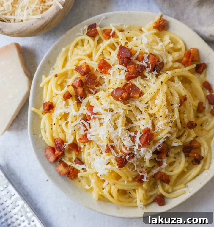 A perfectly plated bowl of homemade spaghetti carbonara, showcasing rich egg yolk sauce, crispy pancetta, and freshly grated Parmigiano Reggiano cheese, ready to be enjoyed.