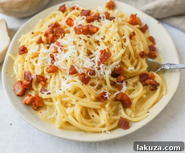 The golden, creamy carbonara sauce coating fresh spaghetti, with visible flecks of black pepper and crispy pork, capturing the perfect texture and color of the dish.