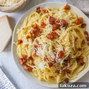 A vibrant bowl of spaghetti carbonara, ready to be served, highlighting the glossy sauce and perfectly cooked ingredients.