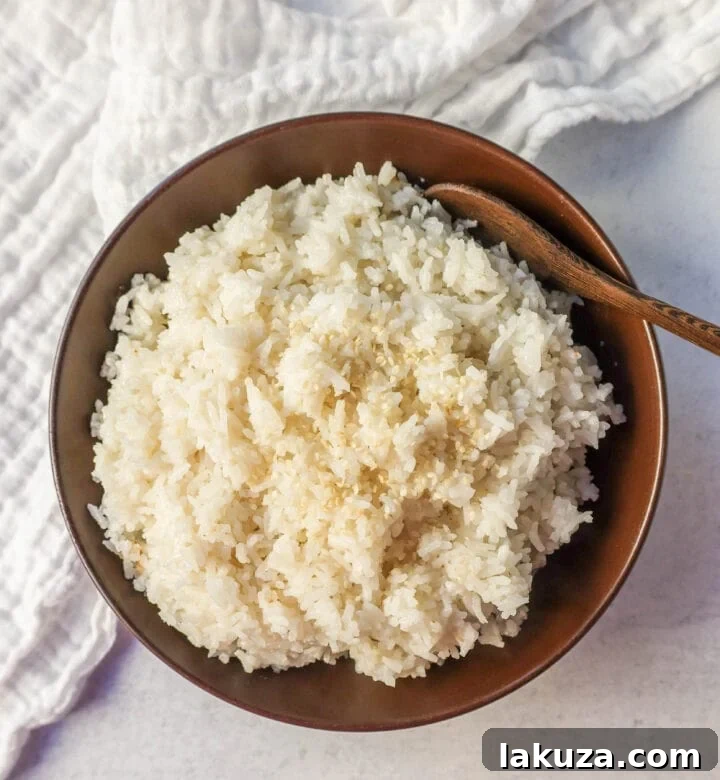 Close-up shot of raw jasmine rice being rinsed in a bowl of water, demonstrating the importance of removing excess starch for fluffy coconut rice.