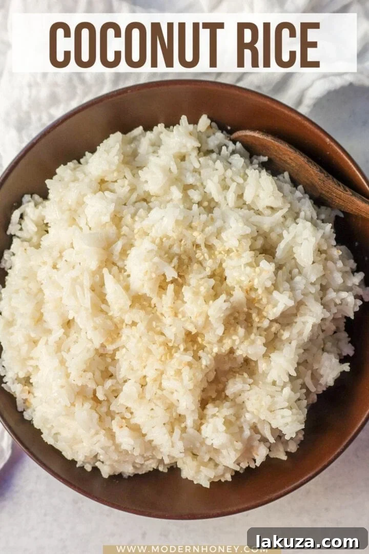 A top-down shot of a large pot of freshly cooked, fluffy Coconut Rice, still steaming slightly, with a spoon ready to serve.