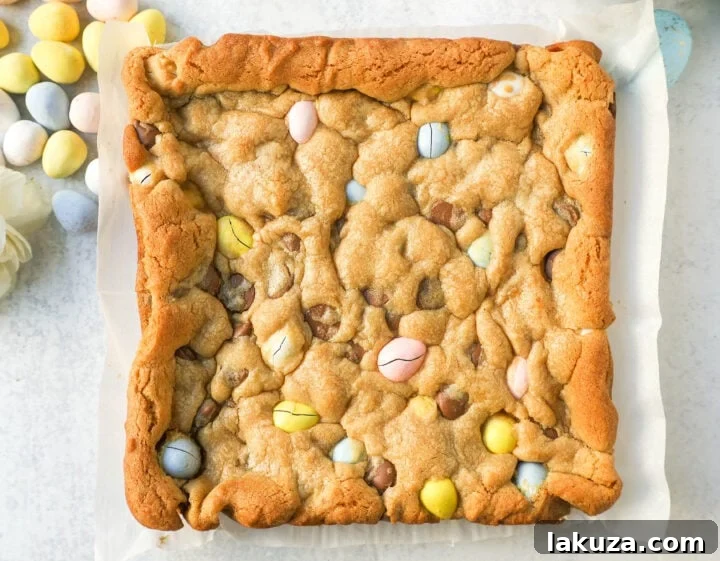 A close-up of a square of Easter Cadbury Mini Egg Blondies, showing the chewy texture and scattered mini eggs.