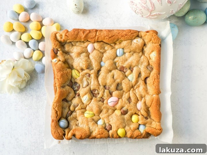 Freshly baked Cadbury Mini Egg Blondies cooling in a parchment-lined baking pan.