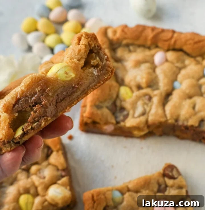 Stack of Cadbury Mini Egg Blondies on a serving plate, dusted with powdered sugar.
