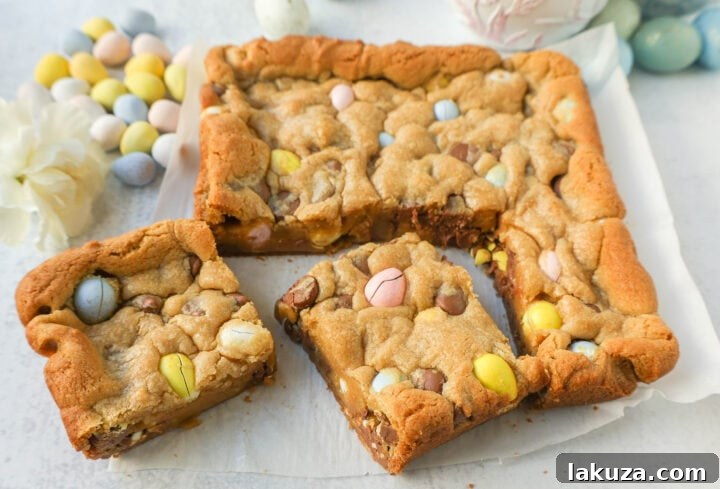 A hand holding a piece of Cadbury Mini Egg Blondie, showing its chewy interior.
