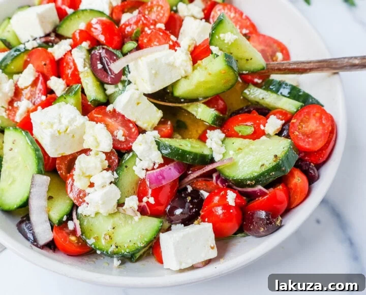 Classic Greek Salad featuring ripe tomatoes, crisp cucumbers, thinly sliced red onion, briny Kalamata olives, and generous chunks of feta cheese.