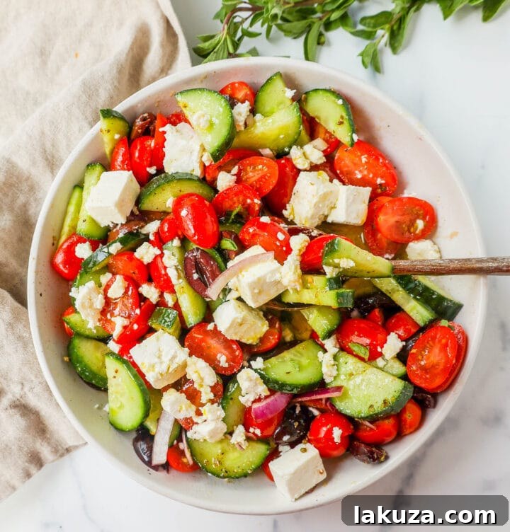 Close-up of a fresh Greek Salad showcasing the vibrant colors of tomatoes, cucumbers, red onion, Kalamata olives, and feta cheese.
