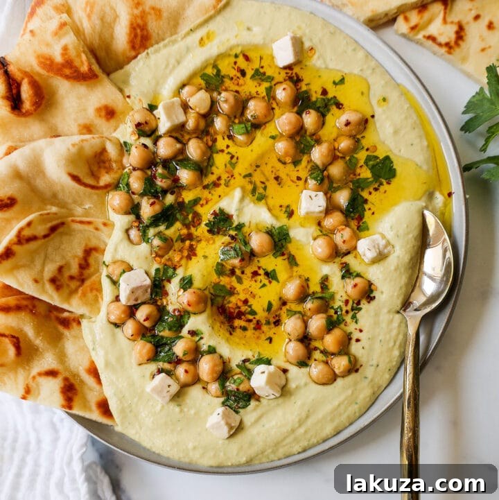 Golden Chickpea Perfection 2 Authentic creamy homemade hummus drizzled with olive oil and garnished with a few chickpeas and paprika, served in a bowl.
