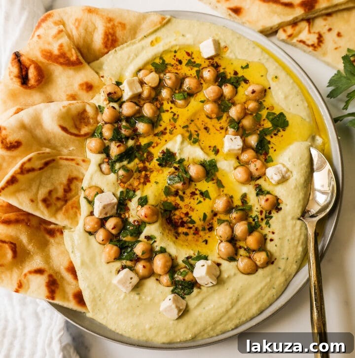 Golden Chickpea Perfection 4 A bowl of creamy homemade hummus garnished with a swirl of olive oil, fresh parsley, and a few whole chickpeas.