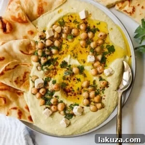 Golden Chickpea Perfection 6 Authentic creamy homemade hummus served in a bowl, garnished with a swirl of olive oil and chickpeas.